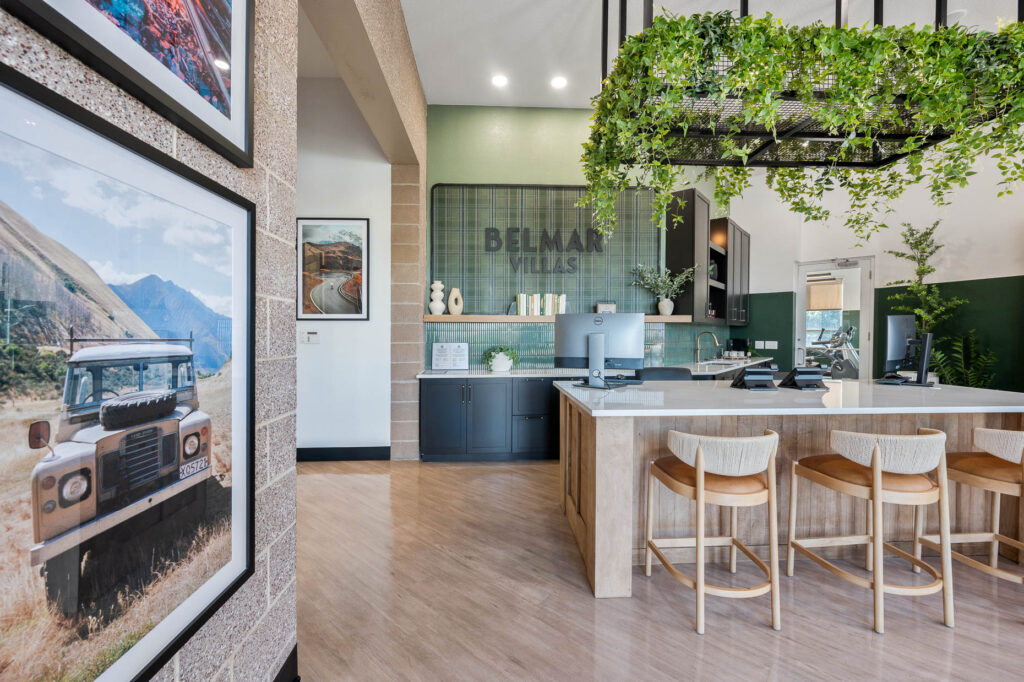 Belmar Villas logo on the wall above cabinets and countertops lining a wall behind a reception space in a leasing office
