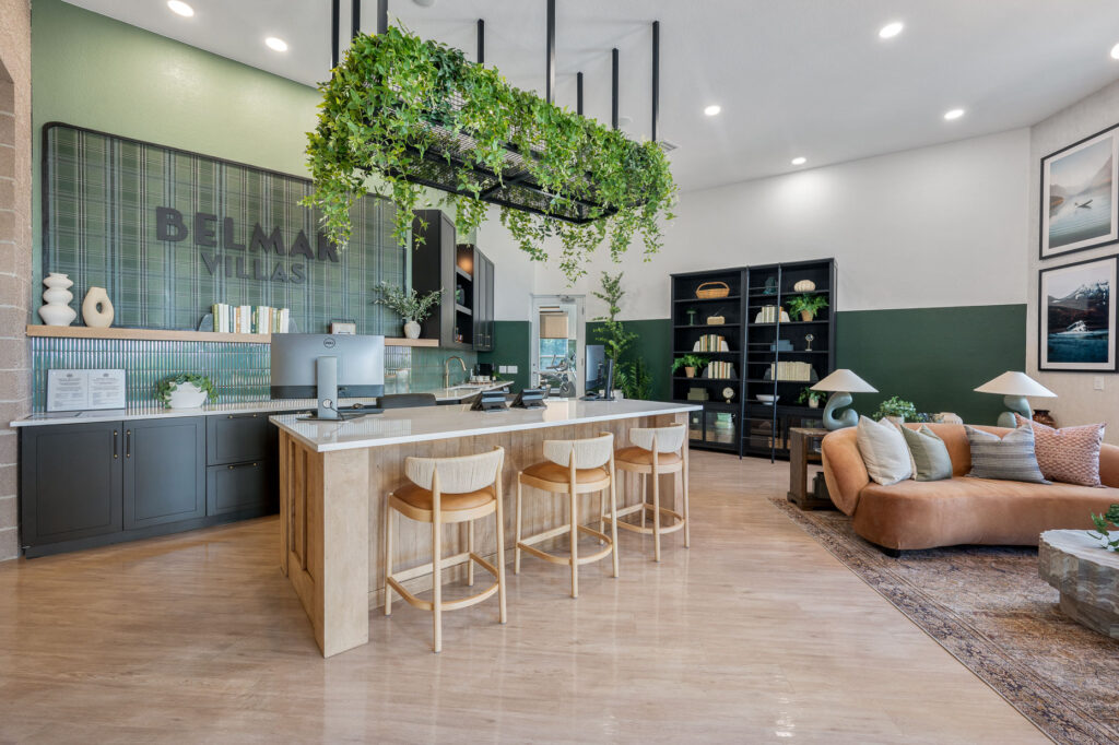 Leasing office entry space with reception space, bookshelf and ladder, and a sofa in an indoor lounge seating space