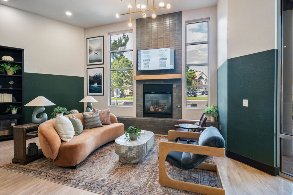 Leasing office entry space with armchairs and sofa seating next to a television mounted above a fireplace
