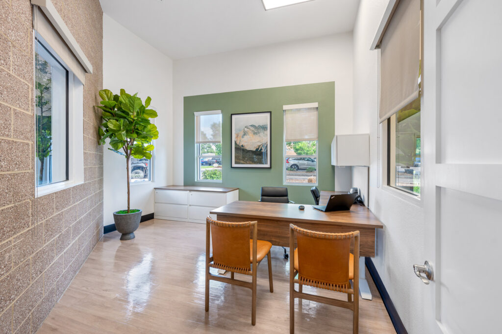 Leasing office meeting room with desk and office chairs, laptop and filing cabinet system